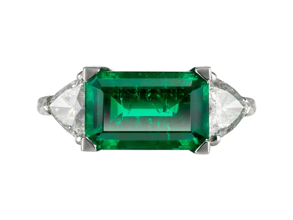 Colombian emerald and diamond flanked solitaire ring.