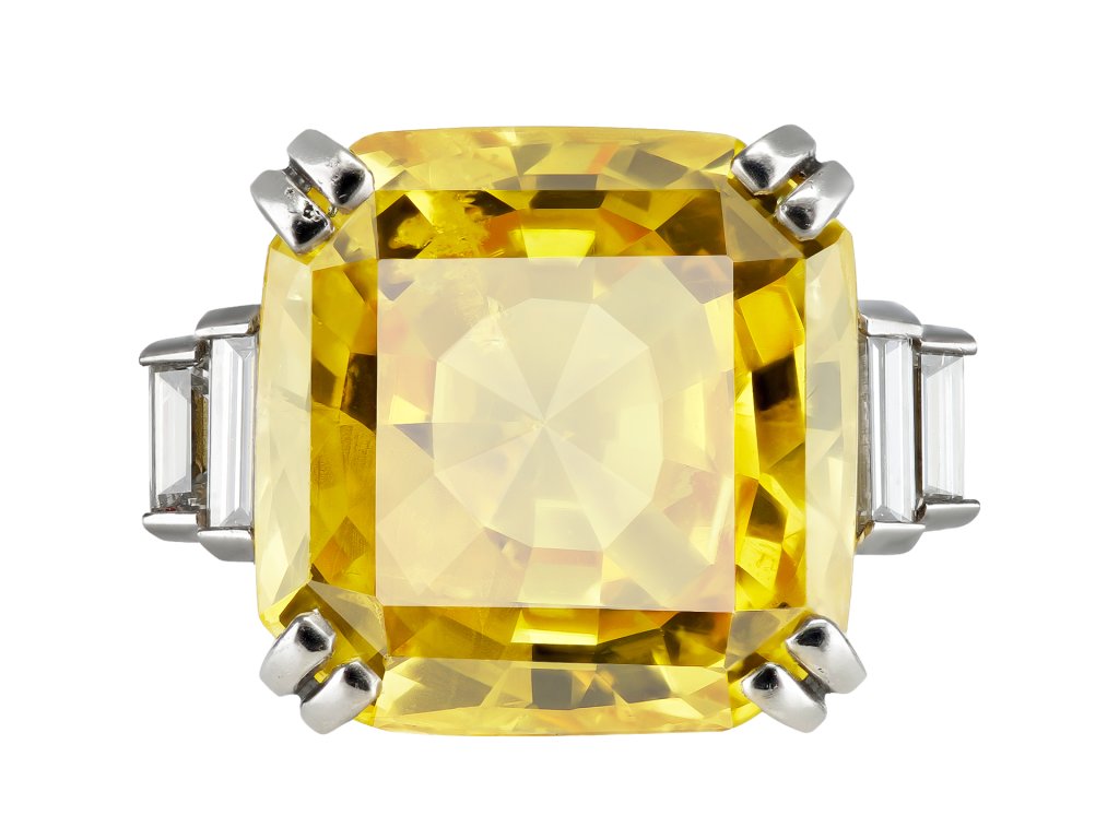 Yellow Ceylon sapphire and diamond flanked solitaire ring, mid 20th Century. 