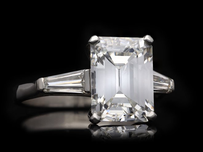 Emerald cut diamond flanked solitaire ring, circa 1960. Hatton Garden