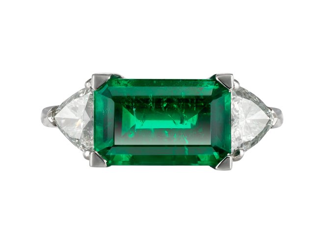 Colombian emerald and diamond flanked solitaire ring.