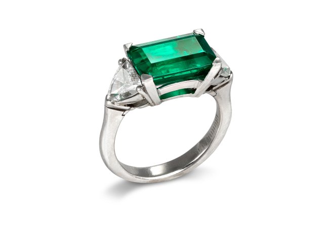 Colombian emerald and diamond flanked solitaire ring.