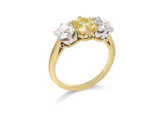 Fancy intense yellow diamond three stone ring, English, circa 1910. 