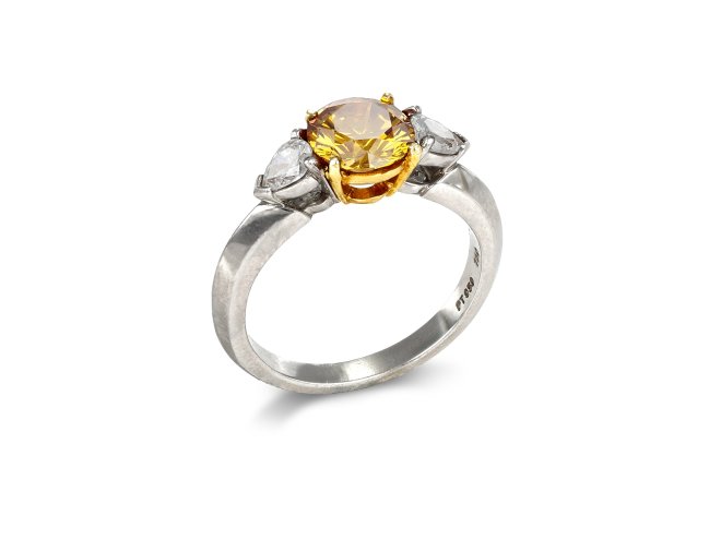 Tiffany & Co Fancy deep orange yellow diamond flanked solitaire, American.